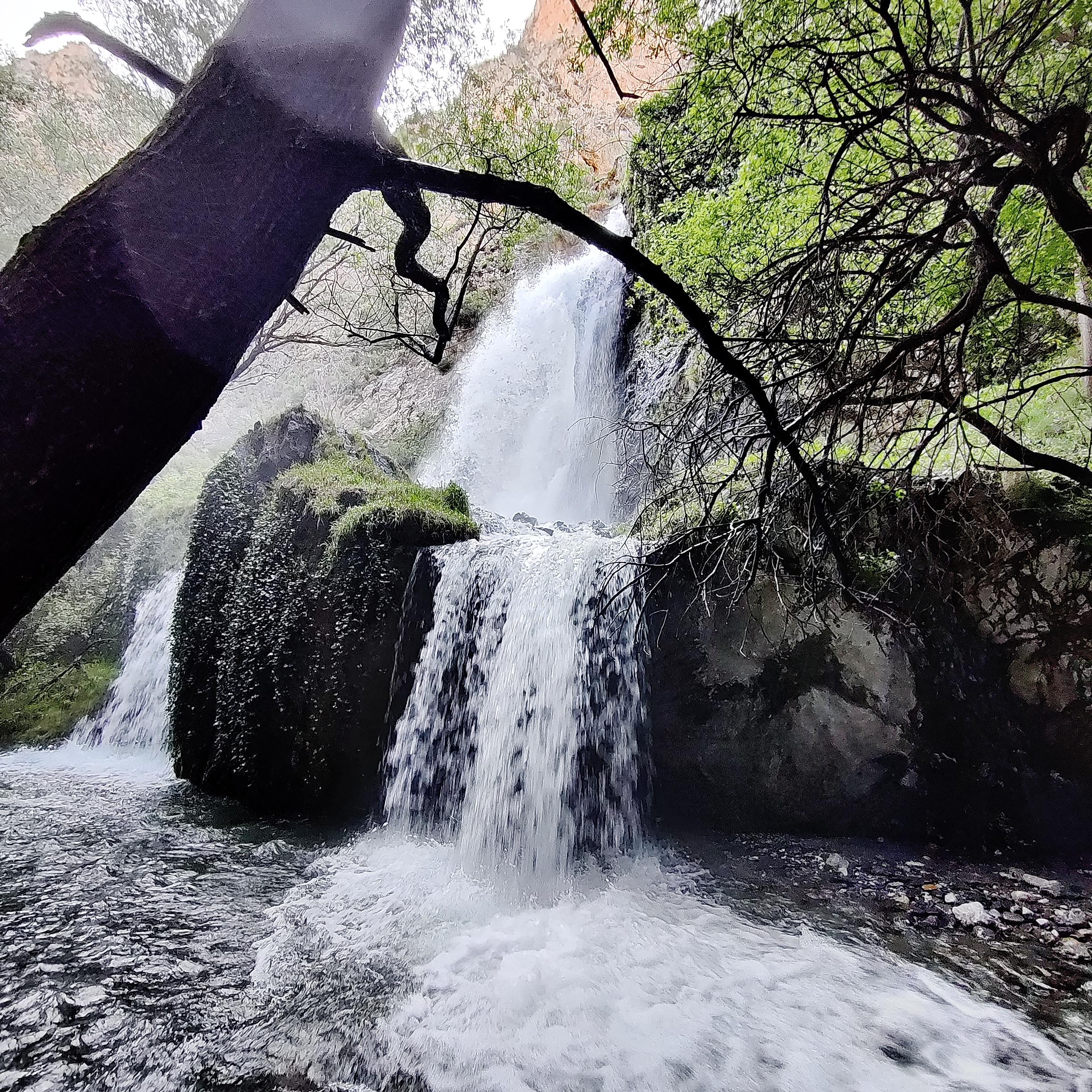 Water falling into big rocks and splashing into a river.