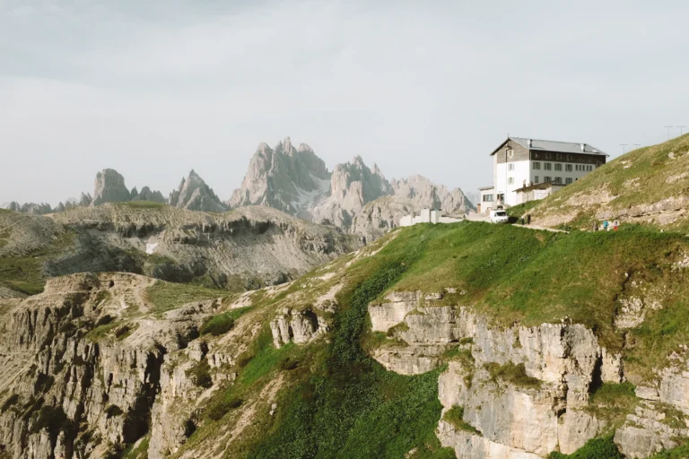 A house perched on a cliff made of white rock and covered in grass.